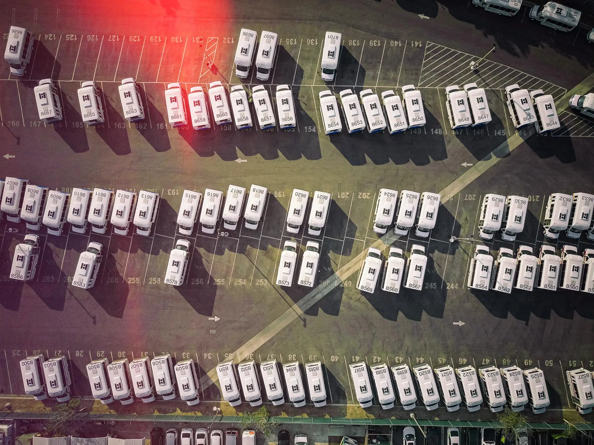 Aerial view of organized van fleet in parking lot with numbered spaces