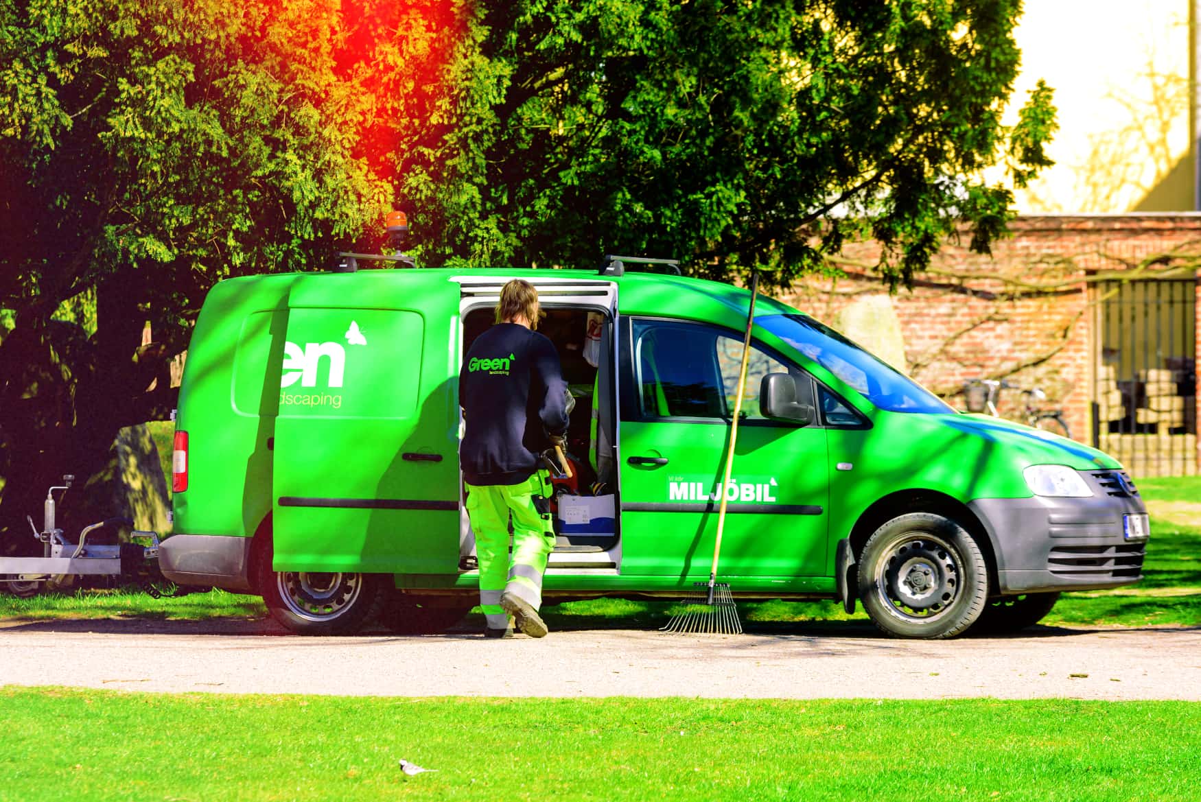 Landscaping professional accessing tracked green maintenance van for optimized grounds management operations
